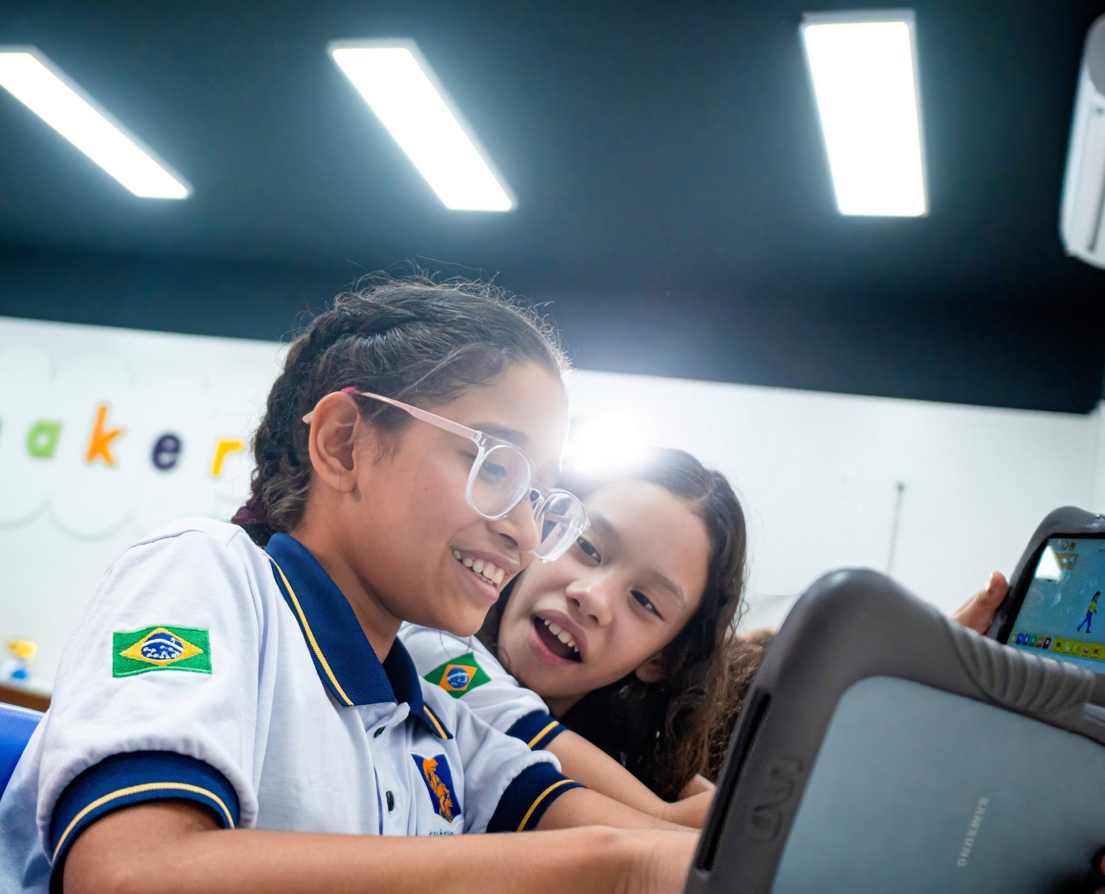 Duas alunas do Palas Atena rindo diante de um tablet na sala maker