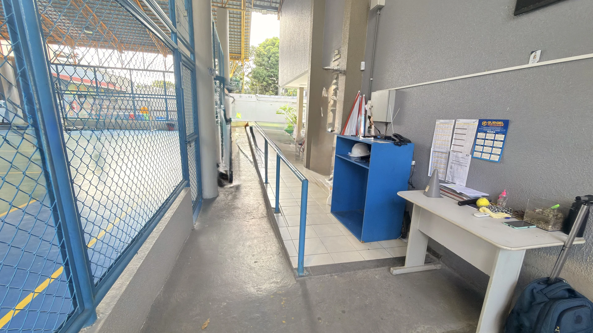 Quadra esportiva com alambrado azul e rampa de acesso no Colégio Palas Atena